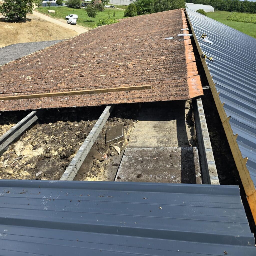 Rénovation de toiture: ancienne couverture en tuiles terre cuite et isolation exposée, adjacente à une nouvelle toiture en tôle métallique grise.