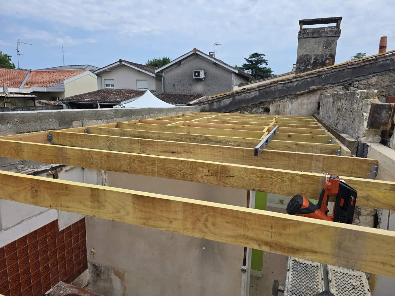 Installation de solives en bois pour une charpente avec outils de mesure et de fixation sur un chantier.