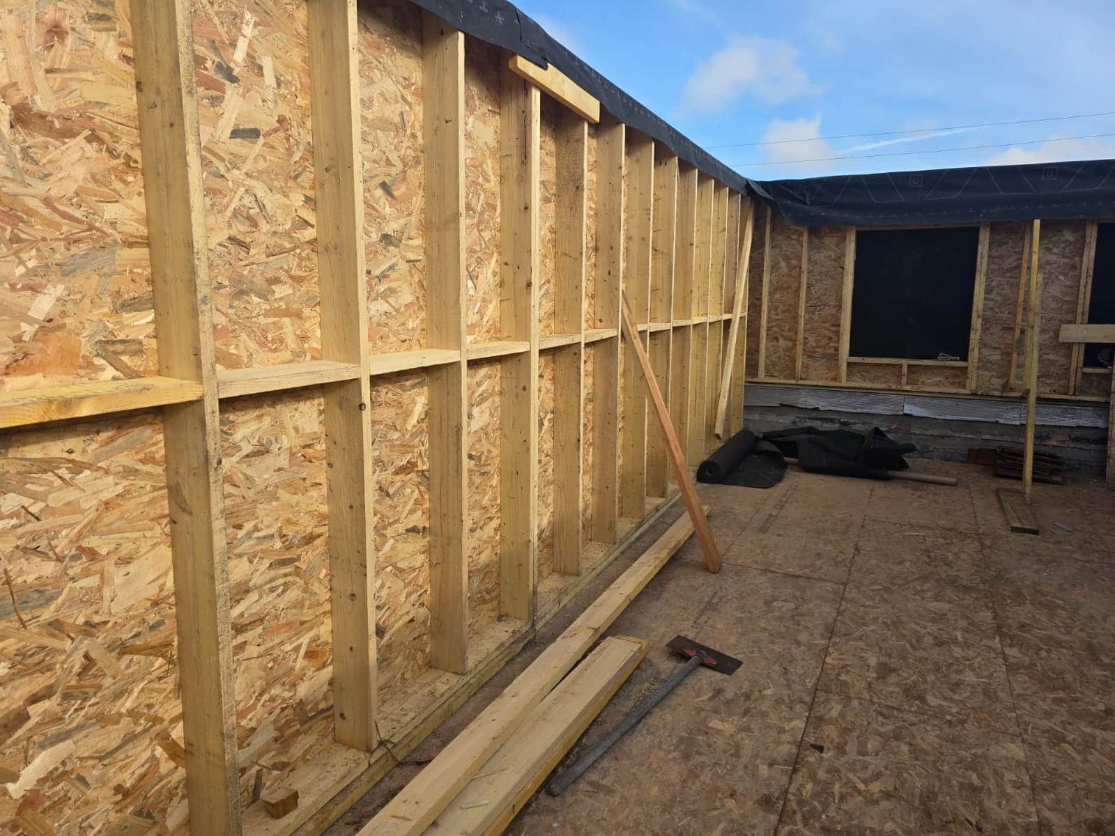 Structure de mur en ossature bois et panneaux OSB sur un chantier de construction extérieur.