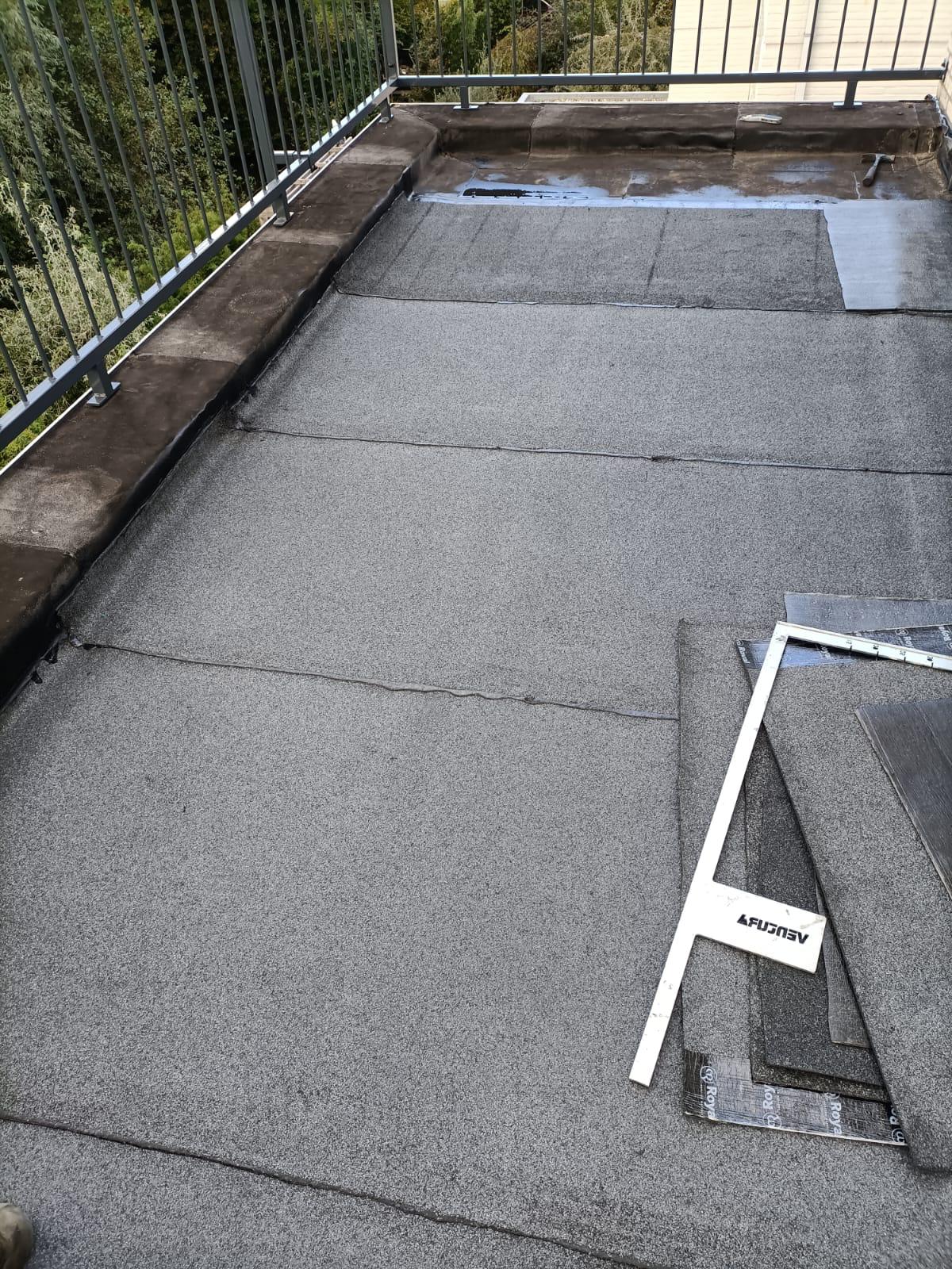 Étanchéité de toiture-terrasse avec membrane bitumineuse grise et équerre FUJISEV pendant les travaux de rénovation.