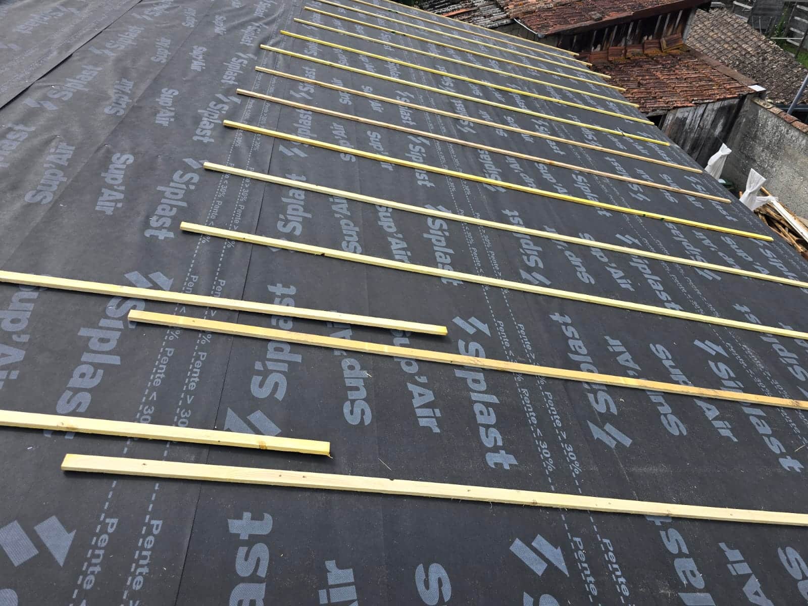 Pose de liteaux bois sur écran de sous-toiture Siplast Sup'Air pour la rénovation d'un toit.