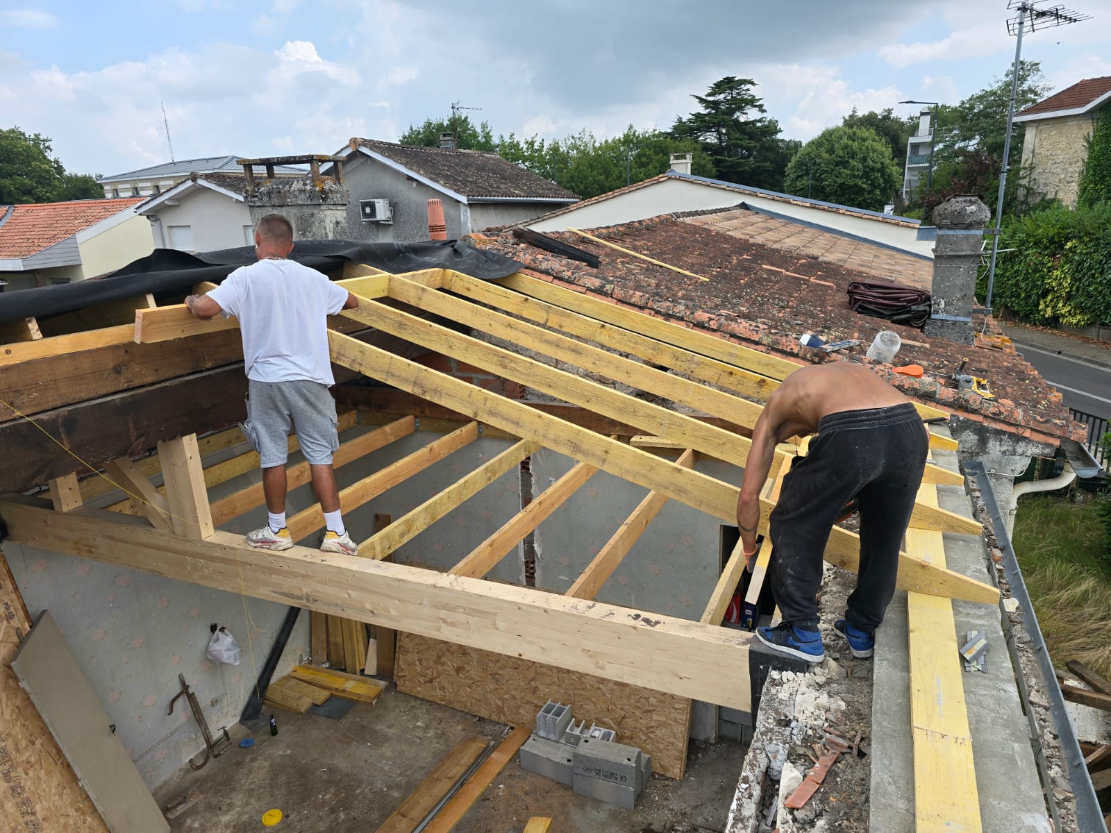Charpentiers installant des chevrons en bois pour la structure d'un toit en rénovation d'une maison individuelle.