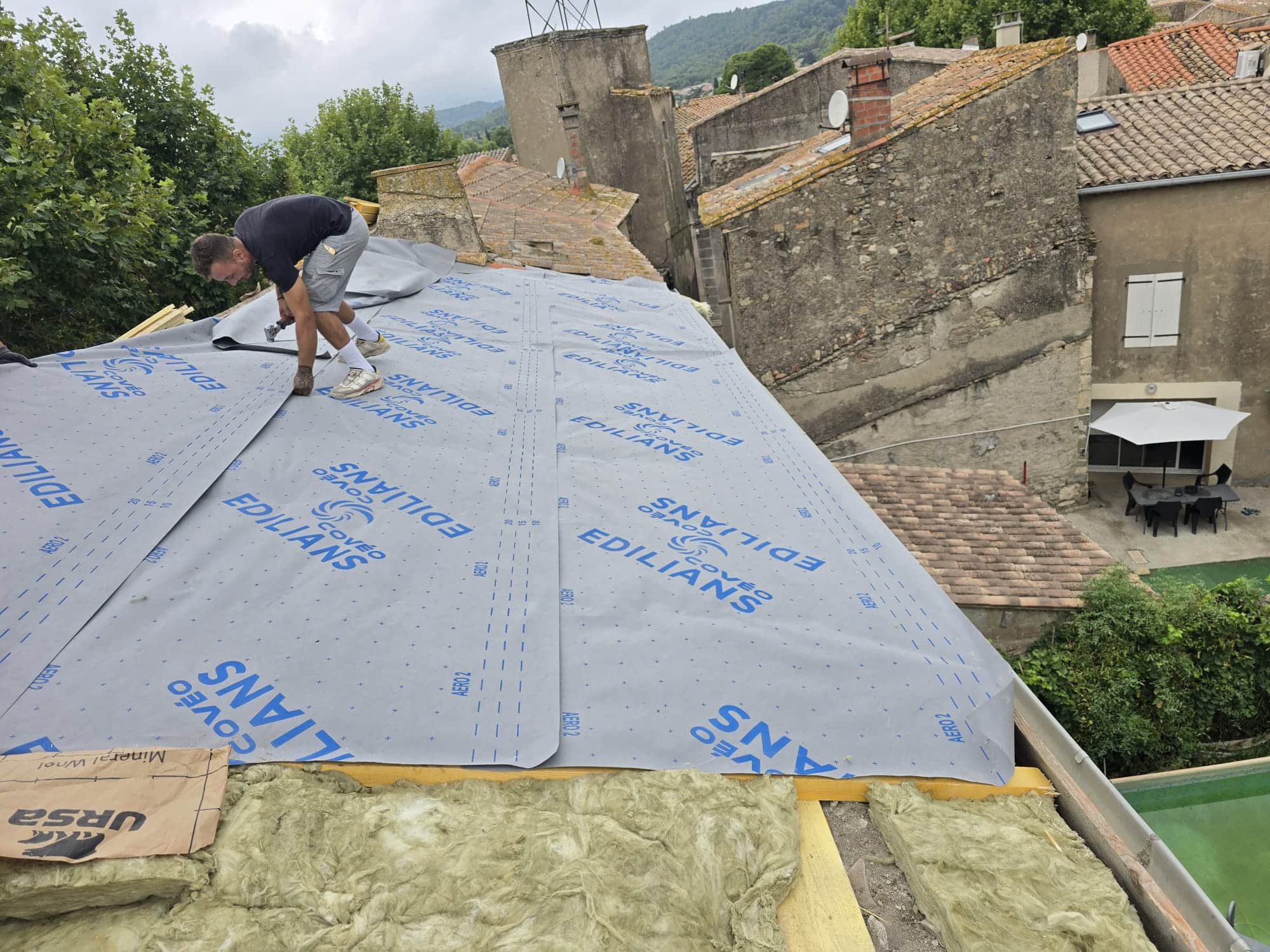 Couvreur posant un écran Edilians Covéo Aero 2 sur isolant URSA lors d'une réfection de toiture.