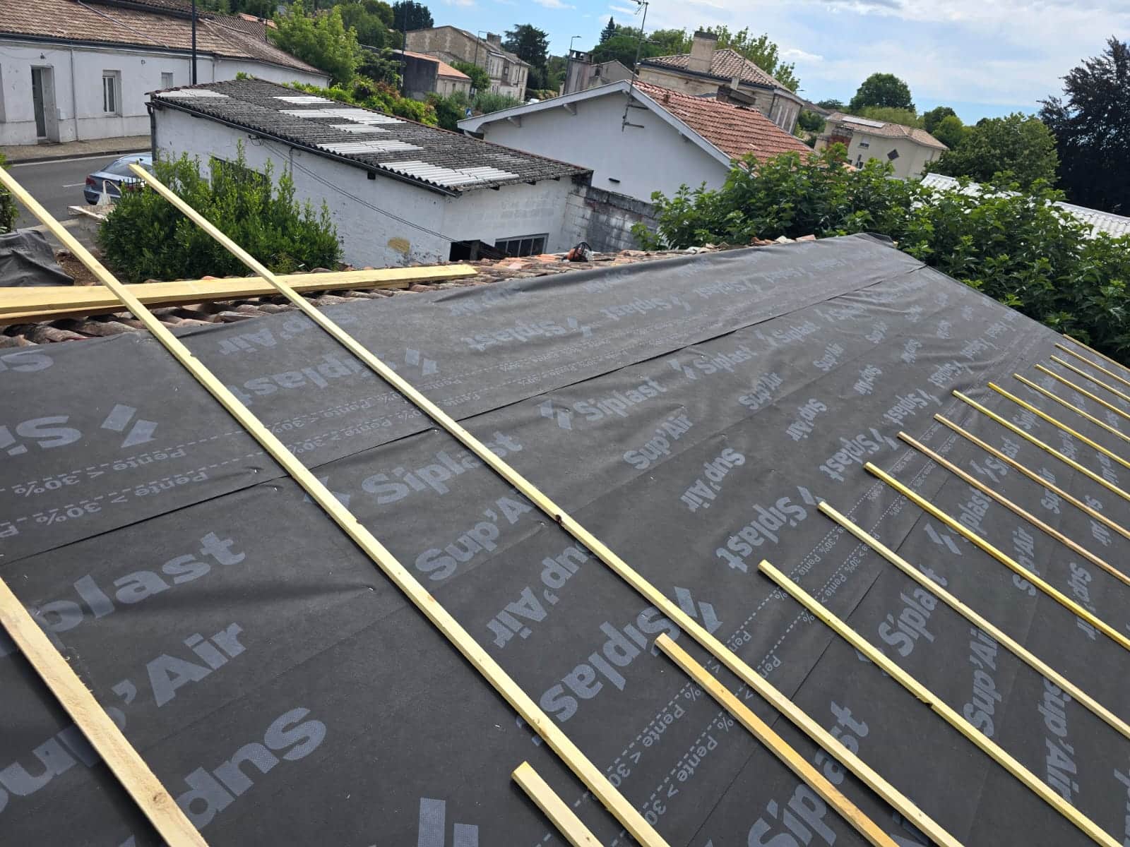 Pose d'écran de sous-toiture Siplast Sup'Air et liteaux sur une charpente en cours de rénovation.