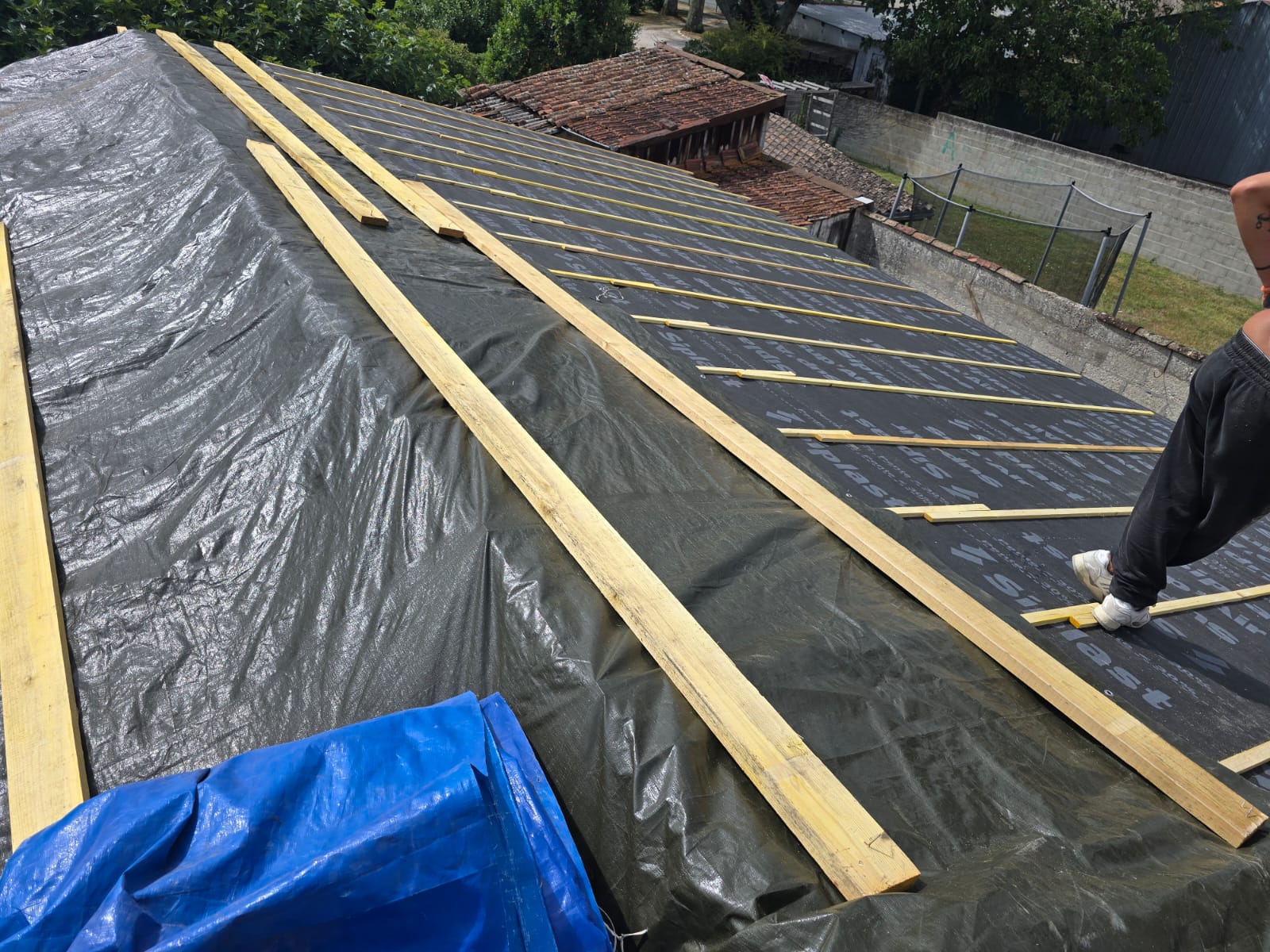 Pose de liteaux en bois sur un écran de sous-toiture Siplast lors d'un chantier de rénovation de toit.