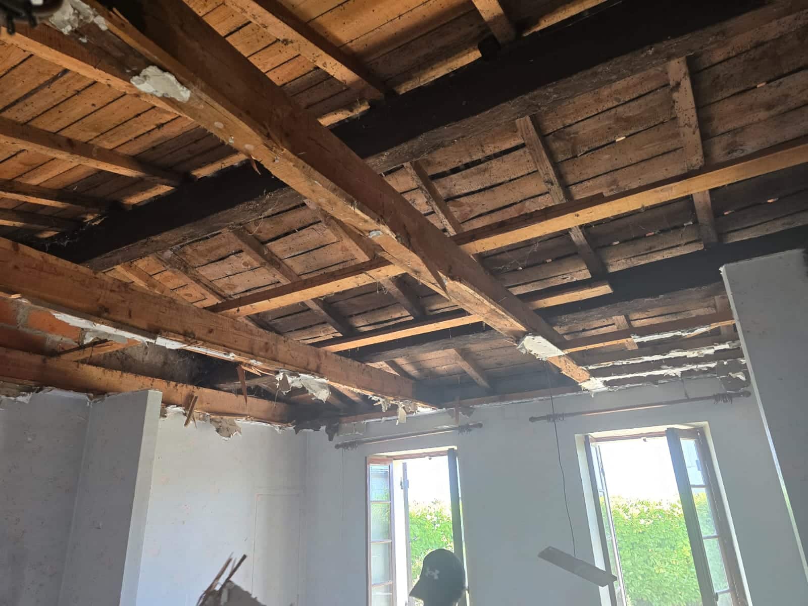 Poutres apparentes en bois lors de la rénovation d'un plafond dans une maison ancienne en travaux.