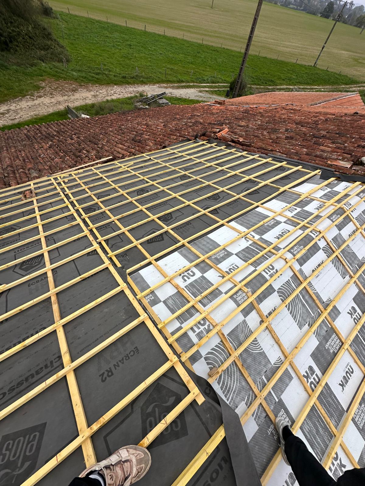 Installation d'un écran de sous-toiture Écran R2 Chausson et de liteaux bois sur une charpente en cours de rénovation.