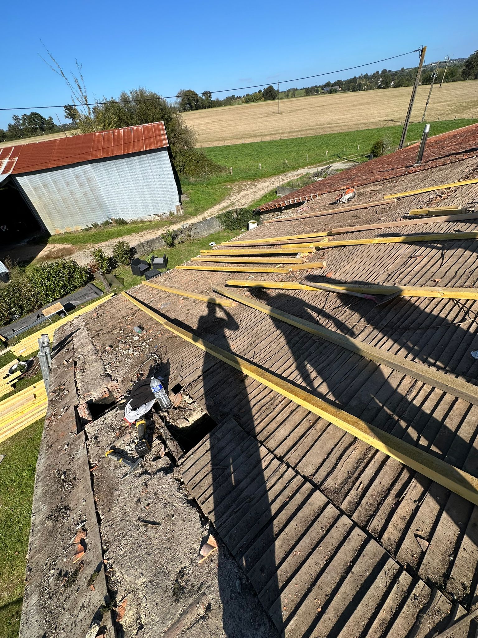 Rénovation de toiture avec pose de liteaux neufs en bois sur une charpente ancienne en zone rurale.