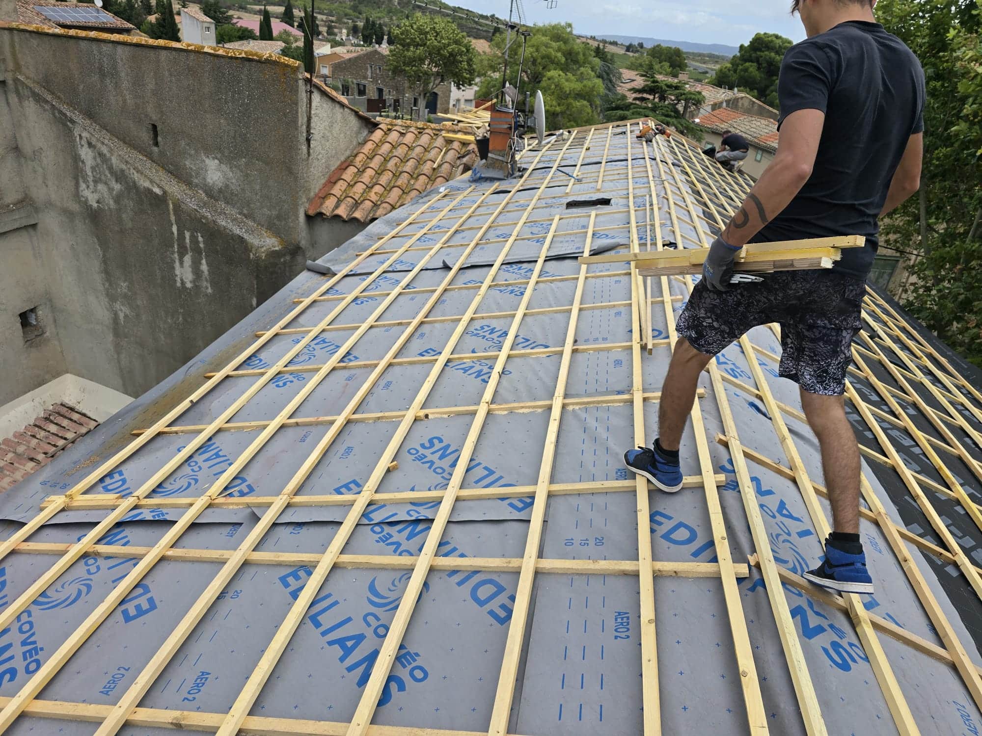 Couvreur installant des liteaux en bois sur un écran de sous-toiture Edilians lors d'une rénovation de toit.